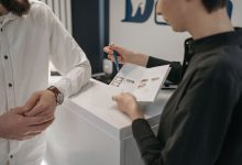 Profissional da recepção orienta uma pessoa no balcão de uma clínica de saúde.