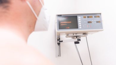 Paciente mascarado em uma clínica sendo monitorado por equipamento eletrônico durante um procedimento médico